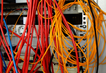 Blaue, rote und gelbe Kabel in einem Geräteschrank.