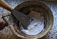 A bricklayer pan with water, plaster and trowel.