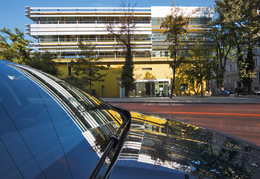 A car in the foreground which reflects the building of the Geological Survey, which is in the background.
